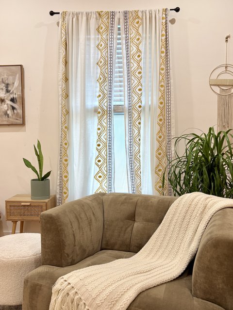The armchair with a knit throw, in front of patterned curtains