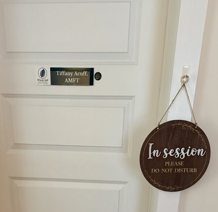 The office door with a "Tiffany Acuff, AMFT" plaque and an "In session, please do not disturb" sign hanging beside it