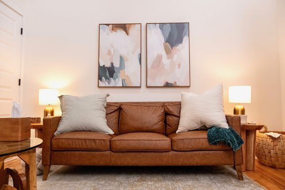 An empty leather couch beneath abstract paintings in Tiffany's Nashville office
