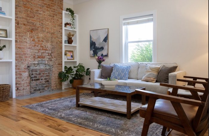 The waiting room: a white sofa, brick accent wall, coffee table, and plants in bright daylight